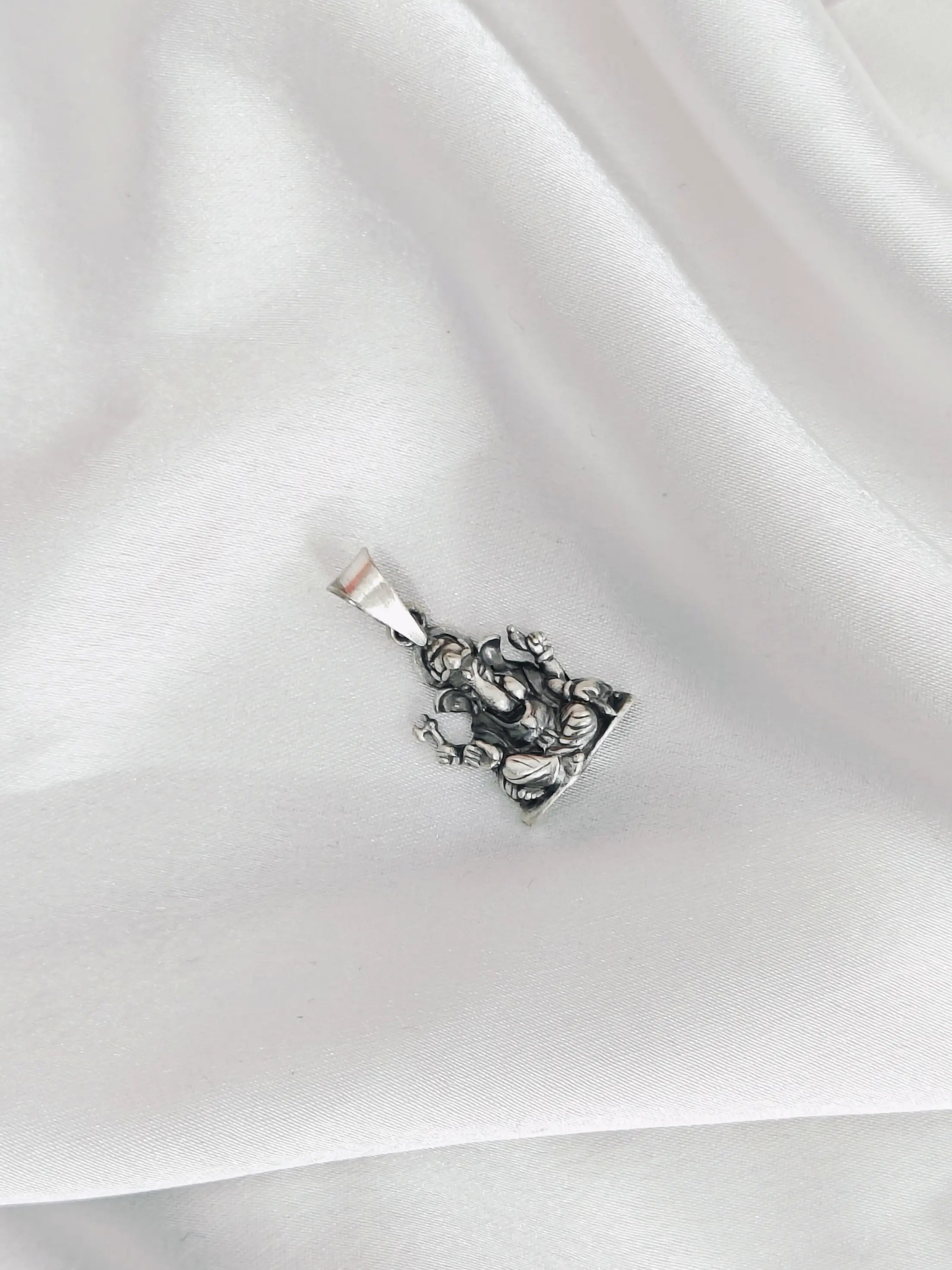 Silver pendant on a white fabric background